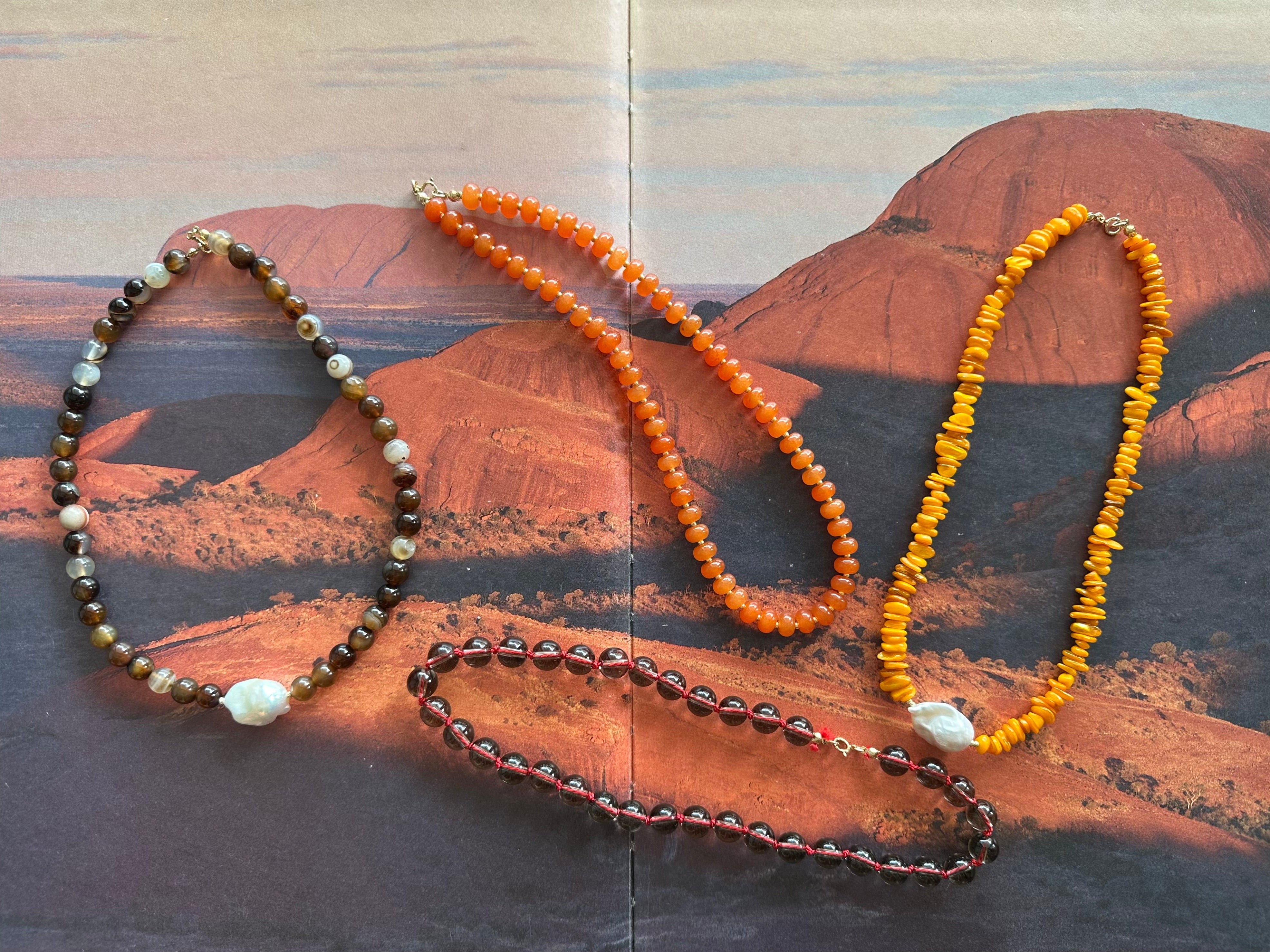 Three beaded necklaces on a textured wooden surface