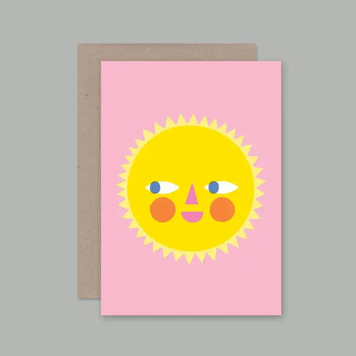 A greeting card with a full-color illustration of a smiling sun on a pink background, paired with a plain envelope.